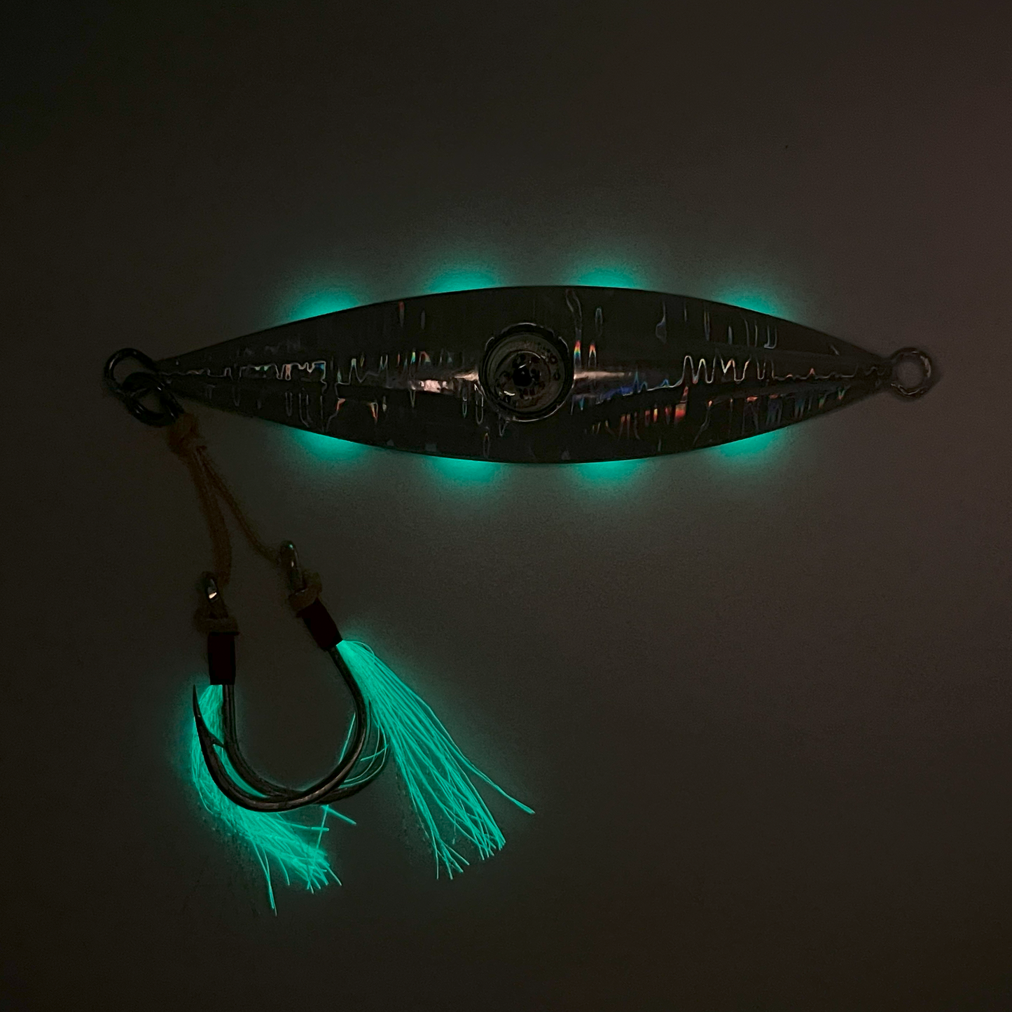 Solid reflective silver back in the dark with skirts glowing. Glow from phosphorescent stripes on front is visible.