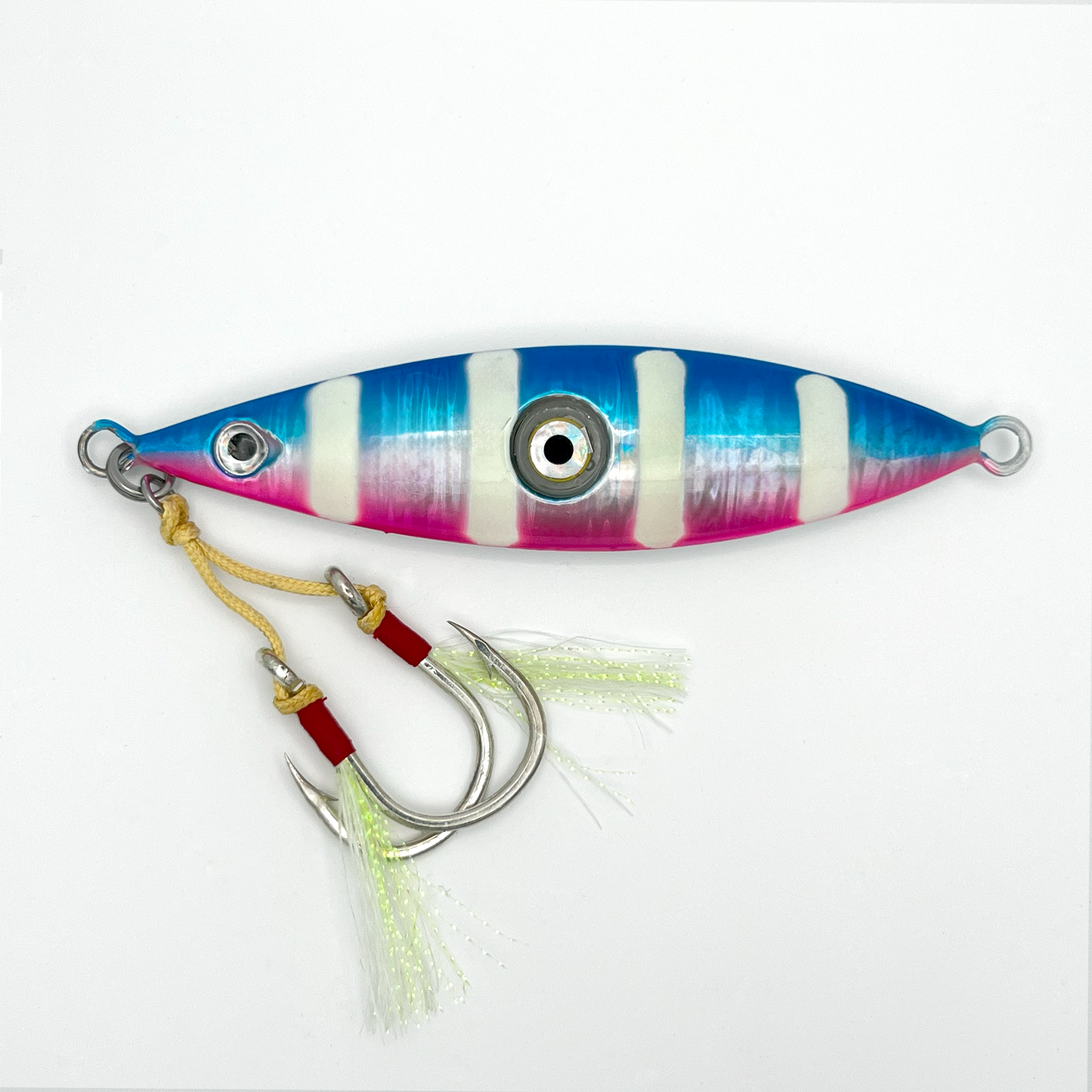Candy Jig fishing lure. Blue top and pink bottom separated by silver horizontal stripe, plus four vertical white stripes, two hooks with skirts, and light-up eye in center.